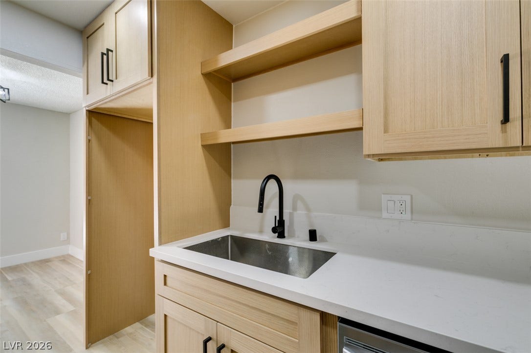 3638 Villa Knolls East Drive, Las Vegas, NV 89120 Custom light wood cabinetry and crisp white countertops define this functional wet bar area.