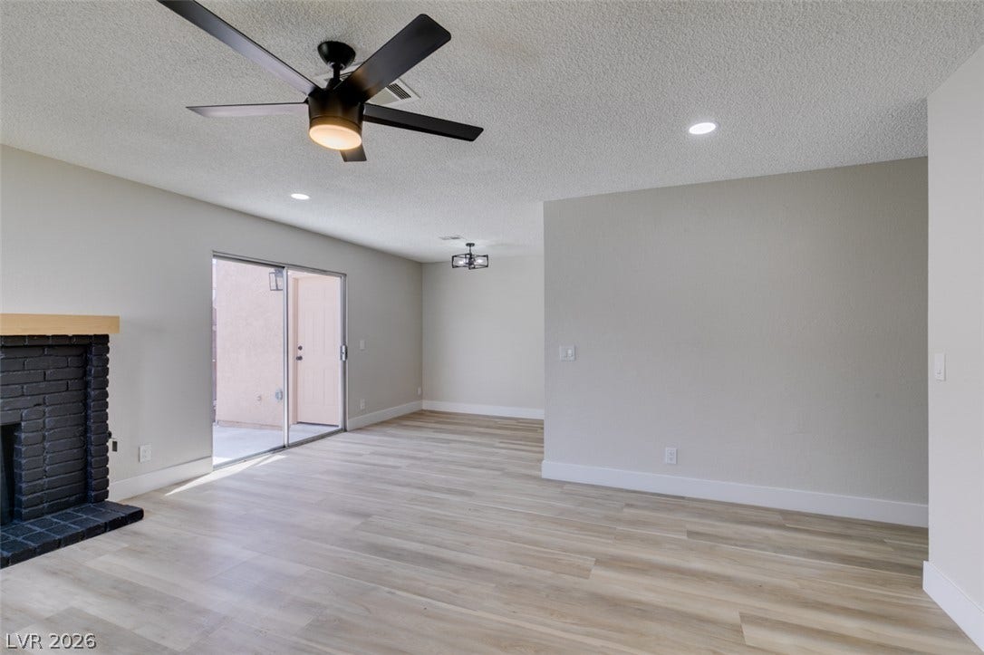 3638 Villa Knolls East Drive, Las Vegas, NV 89120 Smooth wood-look flooring and a classic brick fireplace anchor this versatile open-concept living space.