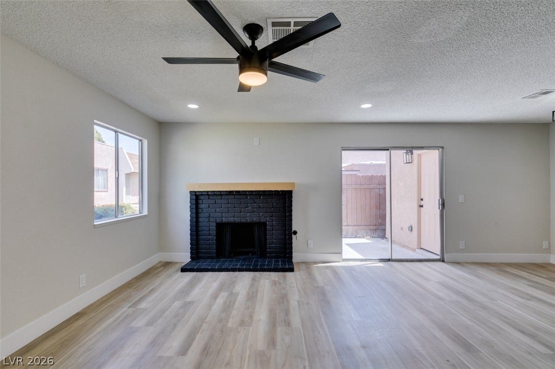 3638 Villa Knolls East Drive, Las Vegas, NV 89120 Smooth wood-look flooring and a brick fireplace anchor this airy living space with outdoor access.