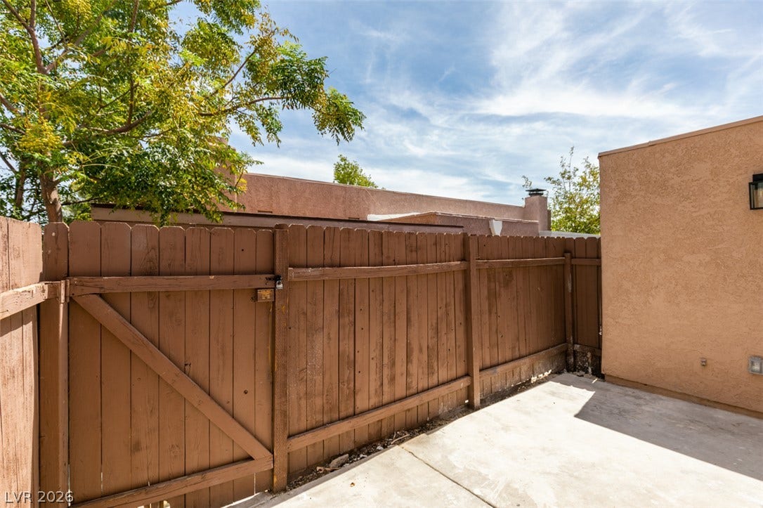 3638 Villa Knolls East Drive, Las Vegas, NV 89120 Solid wooden fencing borders a private concrete patio area under open skies.