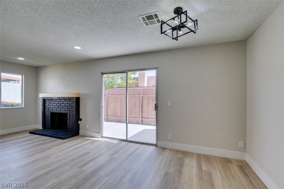 3638 Villa Knolls East Drive, Las Vegas, NV 89120 Plank flooring and a painted brick fireplace anchor this versatile living space.
