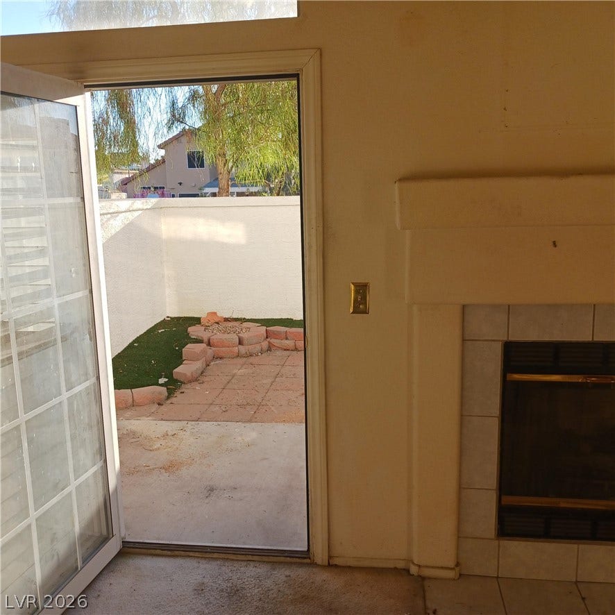 A cozy fireplace sits adjacent to glass doors opening to a private back patio.