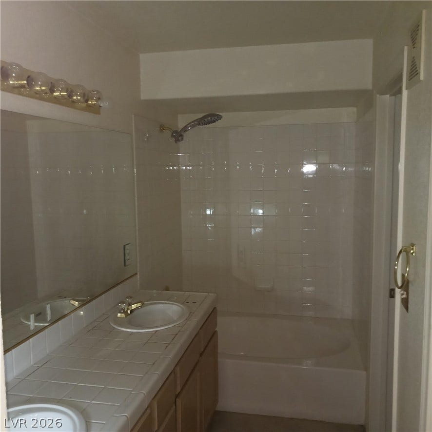 Tiled vanities and a matching shower-tub combination define this functional bathroom space.