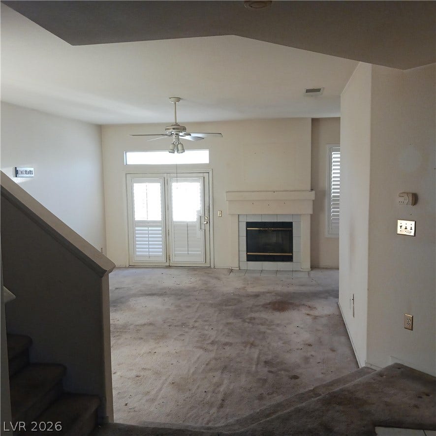 An open living space features a classic fireplace and glass doors leading outside.