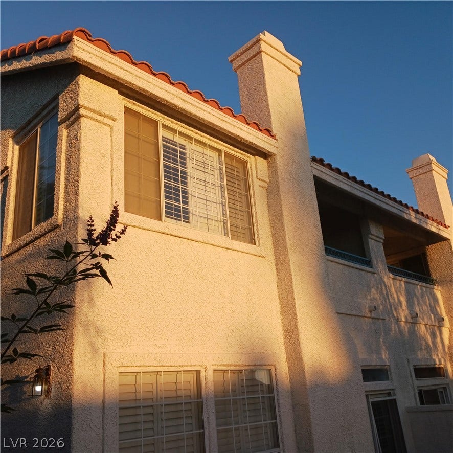 Warm sunlight bathes the classic stucco exterior and tiled roofline of this multi-level home.
