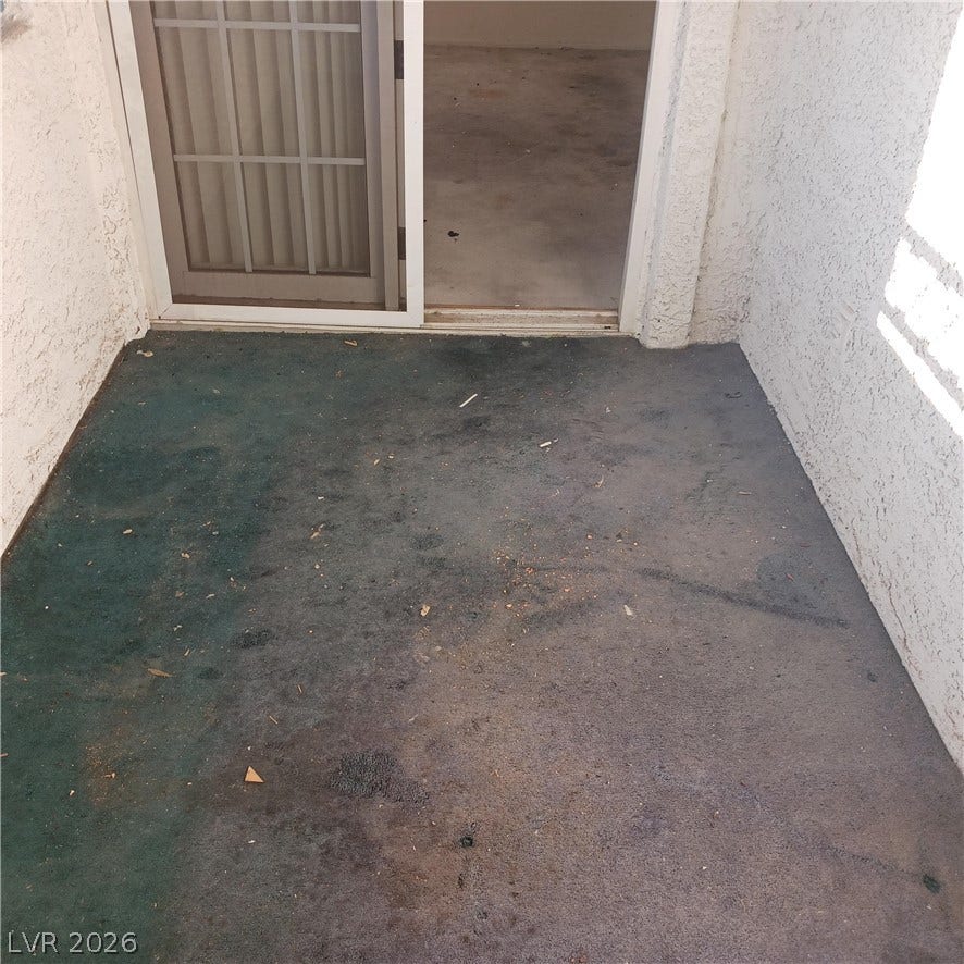A private concrete balcony features stucco walls and sliding door access.