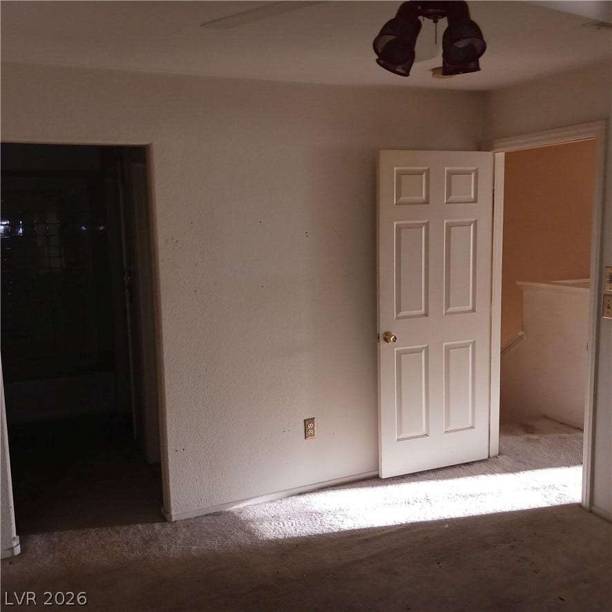 Carpeted flooring and classic paneled doors define this functional upstairs bedroom space.