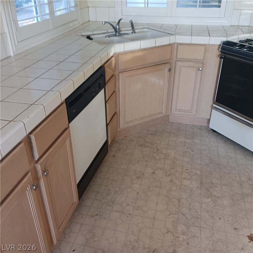 Tiled countertops and classic wooden cabinetry anchor this functional kitchen space.
