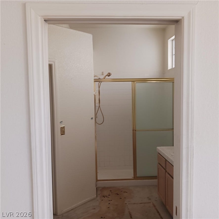An inviting bathroom entryway reveals a glass-enclosed shower stall and vanity cabinet.