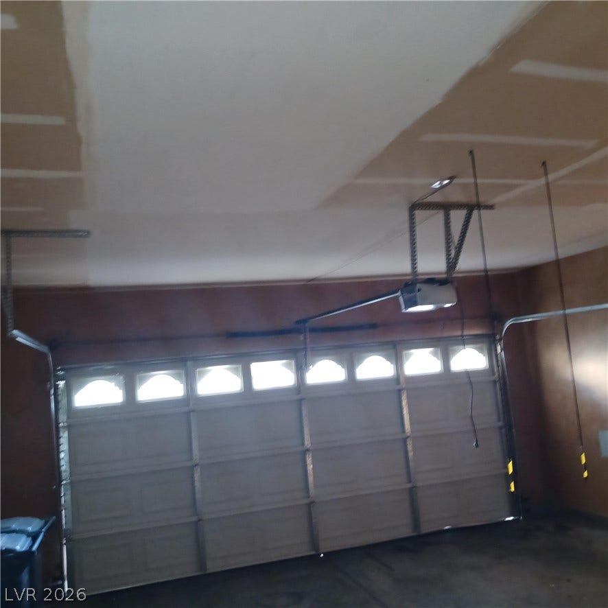 An automatic overhead door brings functionality and natural light to the concrete-floored garage space.