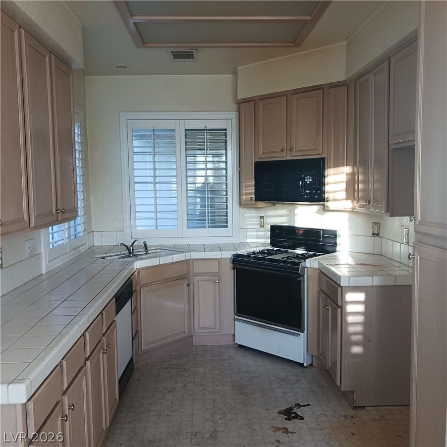 Ample cabinetry and tile countertops maximize preparation space in this functional kitchen layout.