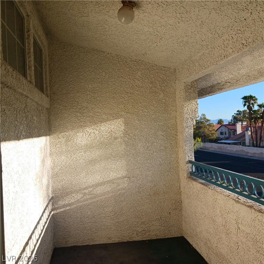 An inviting covered balcony features textured stucco walls and views of the surrounding neighborhood.