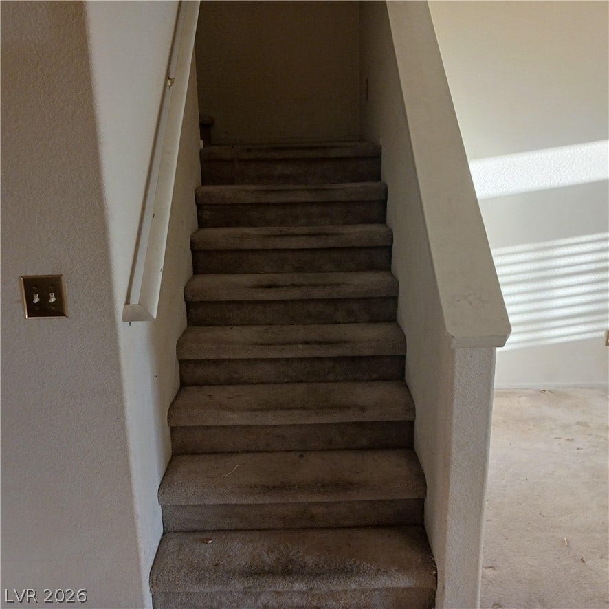 A carpeted staircase with a wood banister leads to the upper level.