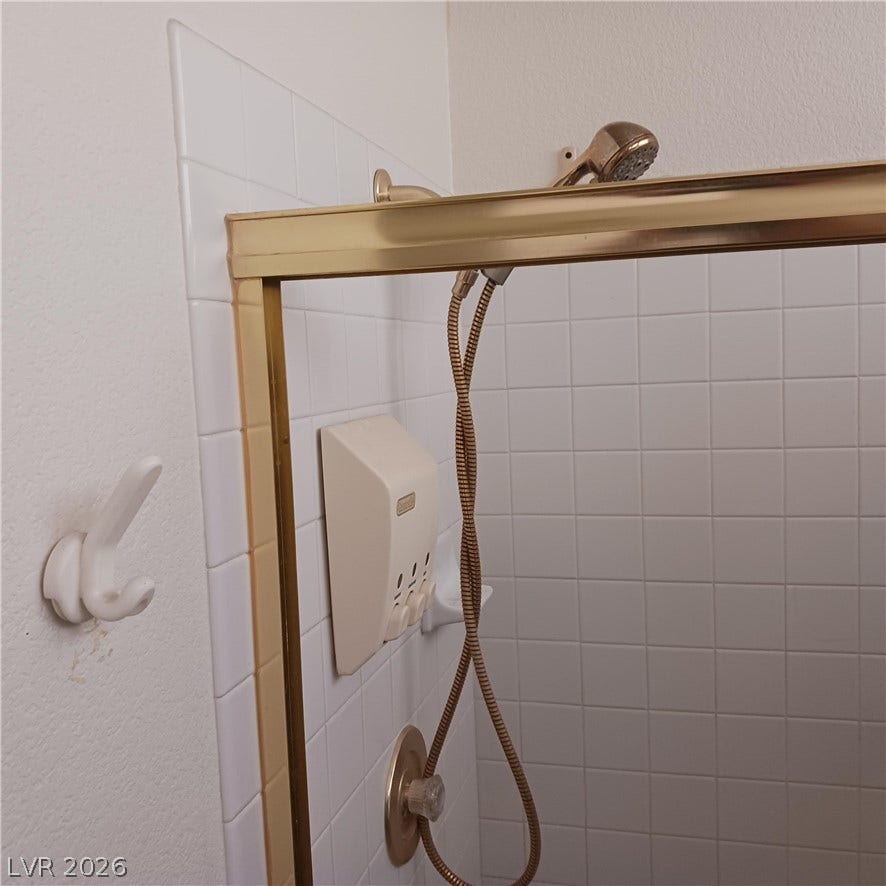 Crisp white wall tile pairs with warm metallic framing in this functional shower enclosure.