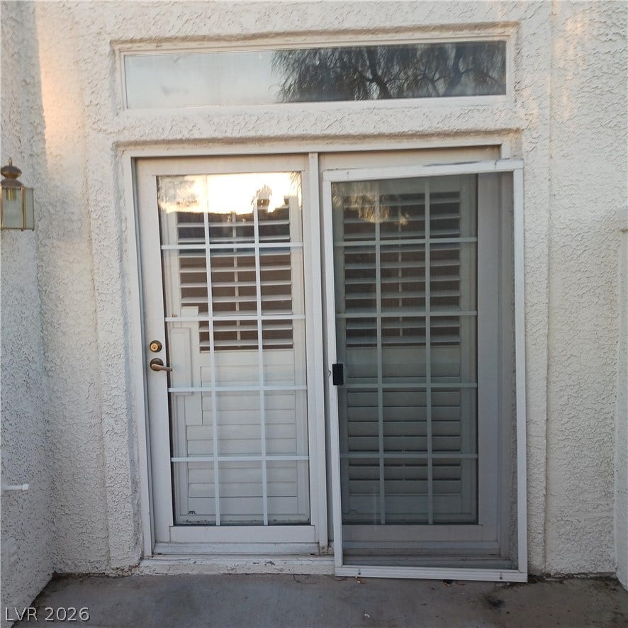 Glass sliding doors with a transom window open directly onto the concrete patio surface.