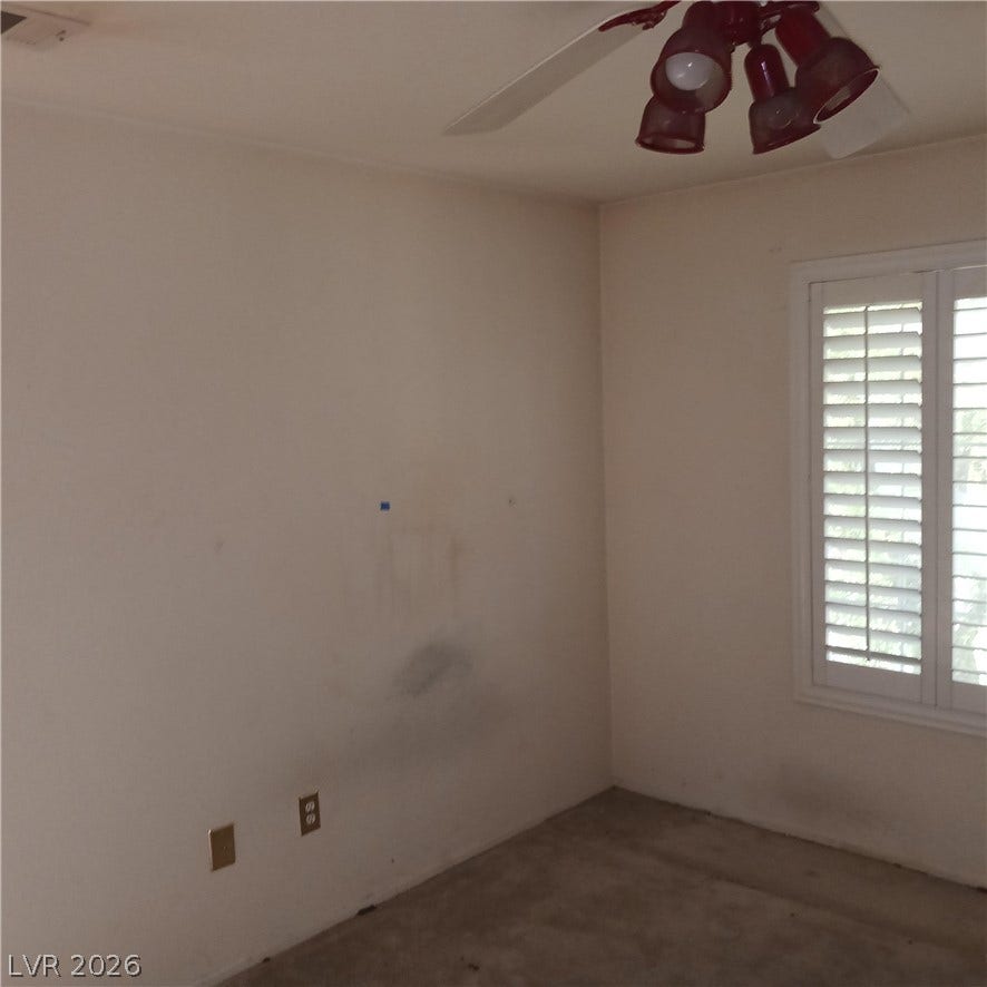 A spacious room features classic plantation shutters and neutral carpet flooring.
