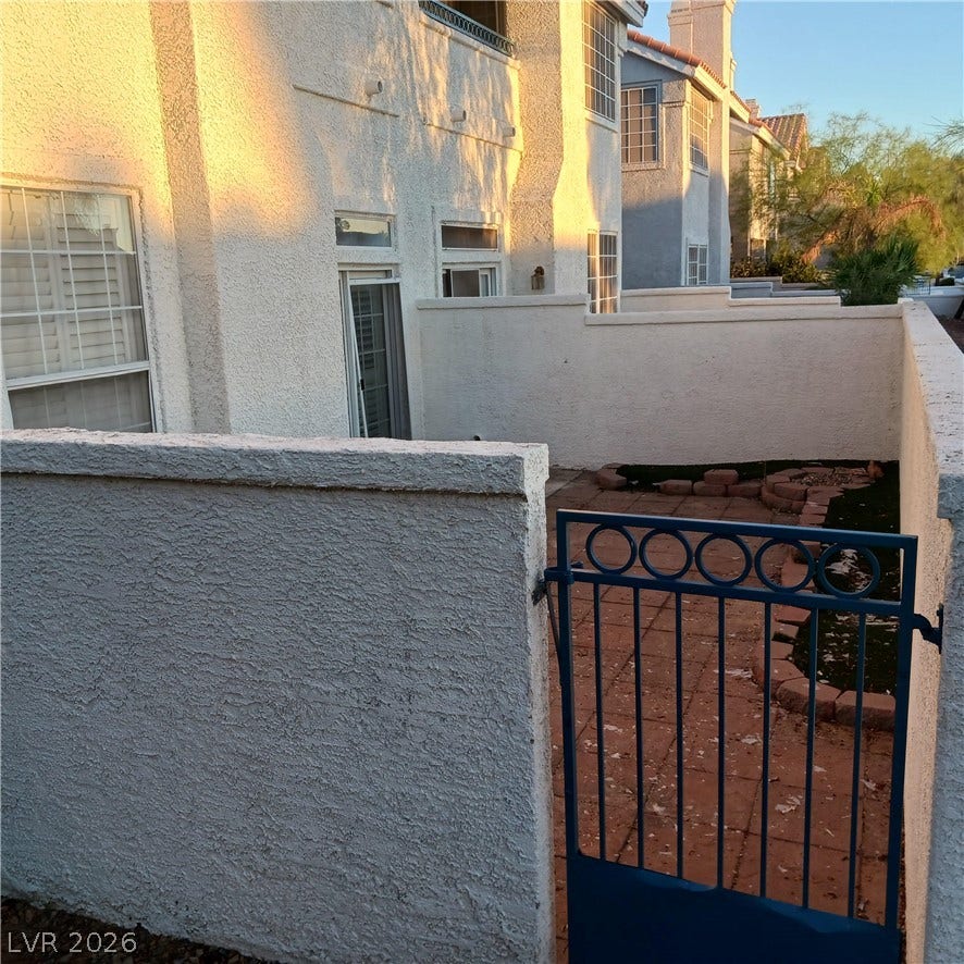 Private stucco walls enclose a cozy paved courtyard entry with a gated access point.