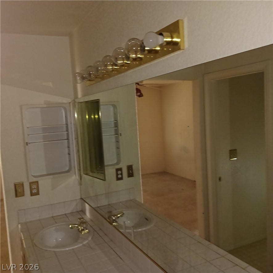 Tiled vanity countertops surround an undermount sink alongside a wide mirror.