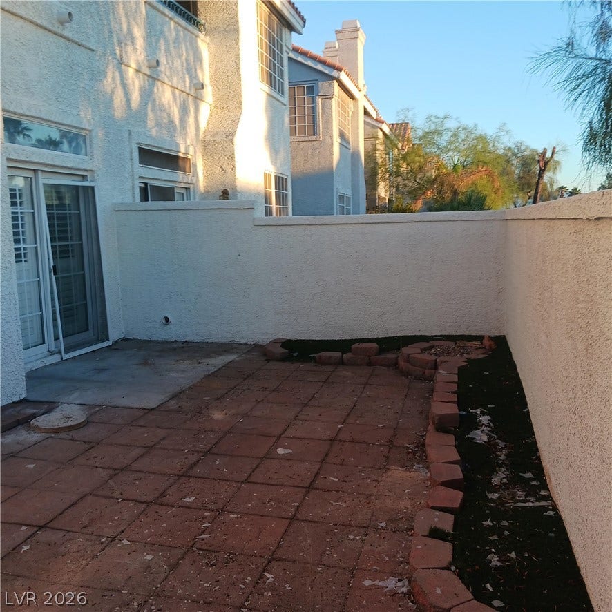 High stucco walls enclose a private tiled patio area situated off the main structure.