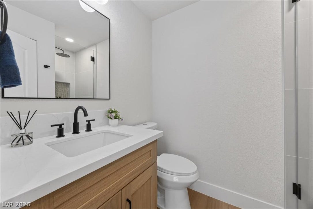 136 Villaggio Street, Henderson, NV 89074 Crisp white walls and clean lines define this modern bathroom with a wood vanity.