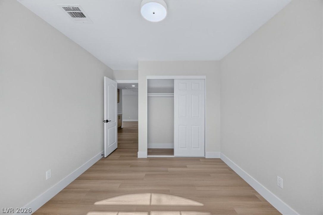 136 Villaggio Street, Henderson, NV 89074 Smooth wood-style flooring and minimalist neutral walls frame this versatile bedroom space.