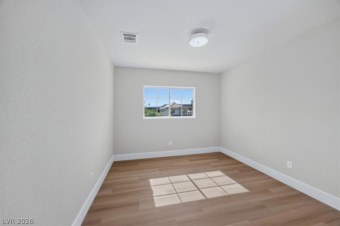 136 Villaggio Street, Henderson, NV 89074 Rich wood-inspired flooring and crisp neutral walls define this versatile secondary bedroom space.