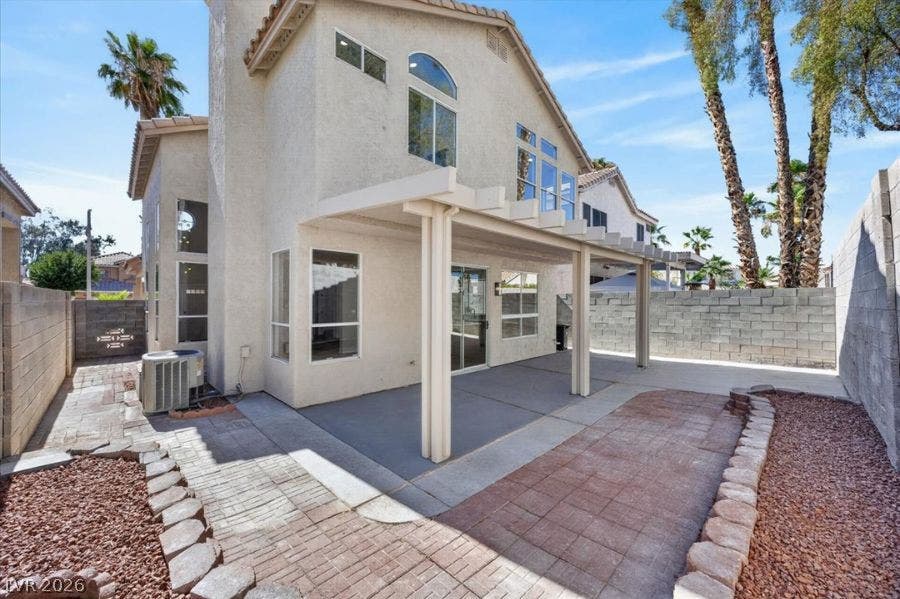 136 Villaggio Street, Henderson, NV 89074 An inviting backyard patio features a structured pergola and concrete walkways alongside a block wall fence.