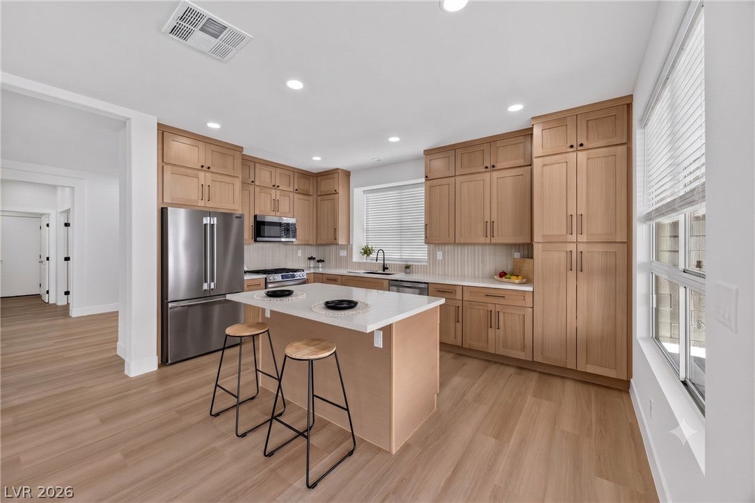 136 Villaggio Street, Henderson, NV 89074 Natural wood cabinetry and a central island ground this light-filled modern culinary space.