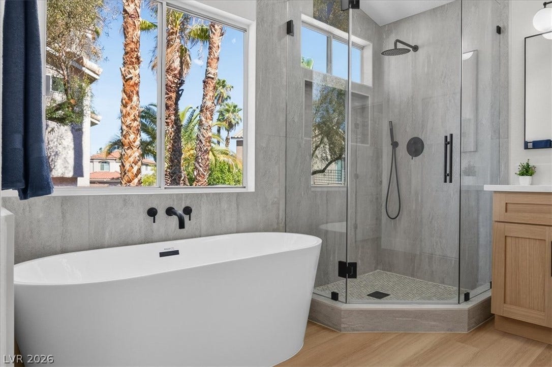 136 Villaggio Street, Henderson, NV 89074 A glass-enclosed shower and freestanding tub elevate this modern bathroom with neighborhood views.