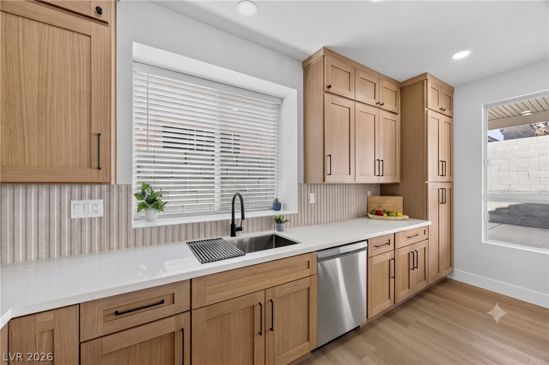 136 Villaggio Street, Henderson, NV 89074 Natural wood cabinetry and sleek solid-surface countertops anchor this modern, light-filled kitchen space.
