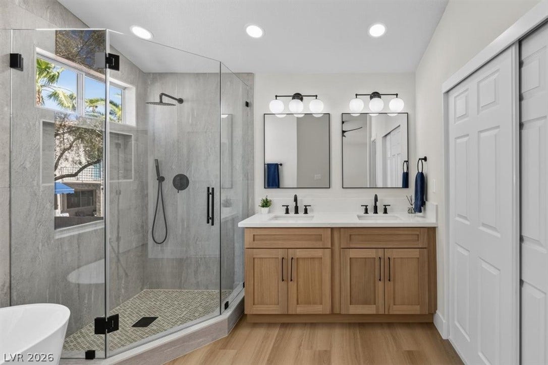 136 Villaggio Street, Henderson, NV 89074 A modern double vanity stands beside a spacious tiled walk-in shower with glass doors.