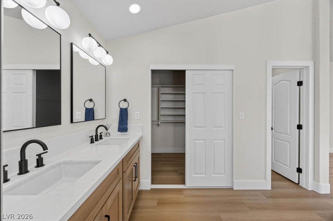 136 Villaggio Street, Henderson, NV 89074 A spacious double vanity and warm wood flooring define this elegant primary bathroom.