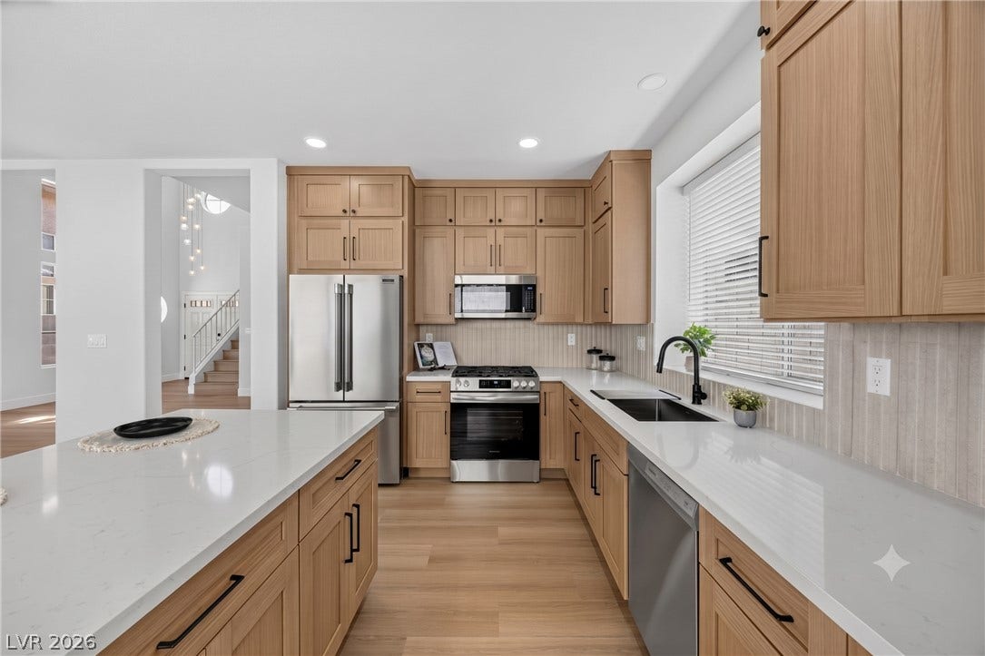136 Villaggio Street, Henderson, NV 89074 Gleaming stone countertops and warm wood cabinetry define this modern kitchen workspace.