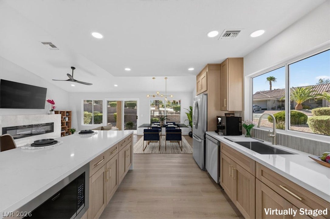 A streamlined kitchen island offers ample counter space, seamlessly connecting to a living area with a sleek linear fireplace.