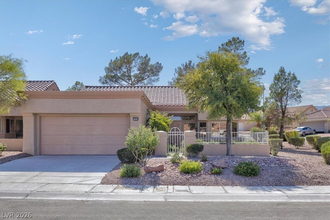 A terracotta-tiled roof crowns this residence, featuring desert-friendly landscaping and an inviting gated entry.