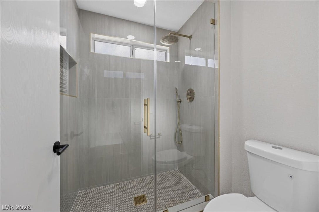 A sleek shower enclosure features a rainfall showerhead, handheld sprayer, and mosaic tile floor.