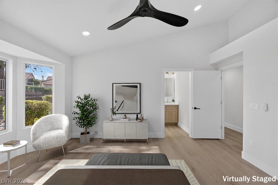 A tranquil primary bedroom features high ceilings, wide plank flooring, and a private en-suite bathroom access.
