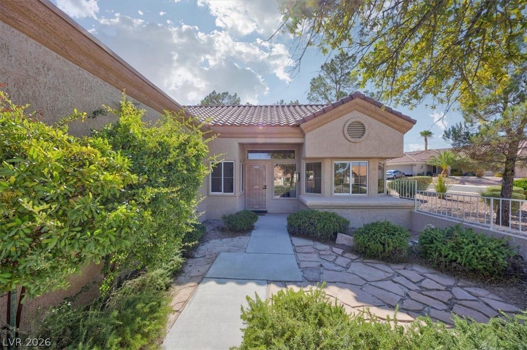 A terracotta tile roof accents this welcoming home with a stone and concrete pathway.