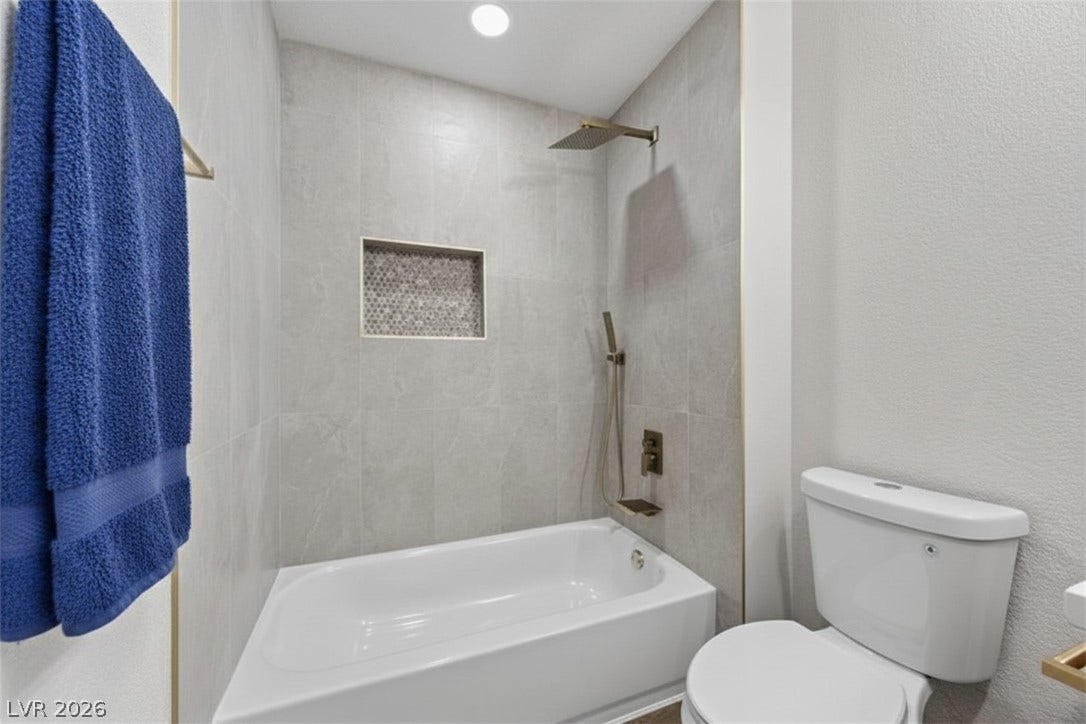 Modern bath with rain shower head and sleek, tiled alcove.