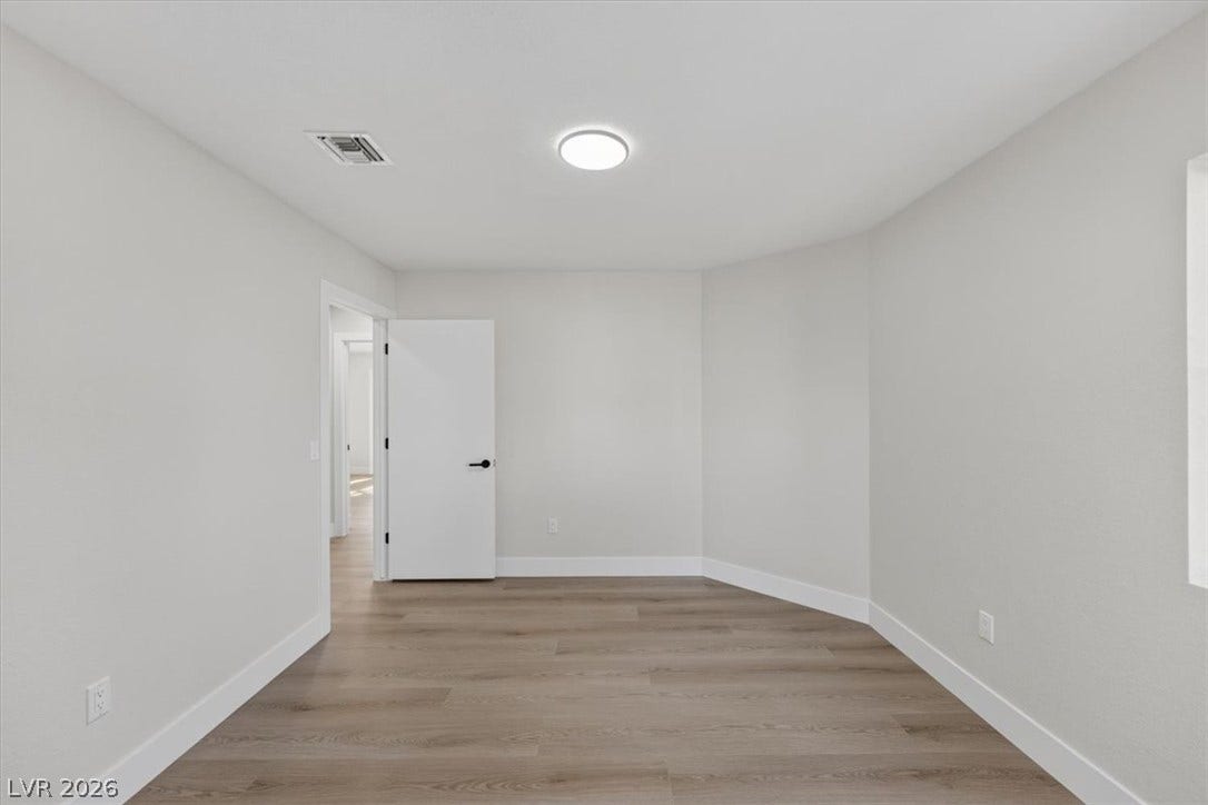A well-lit, neutral-toned room features clean lines and inviting plank flooring, ready for personalization.