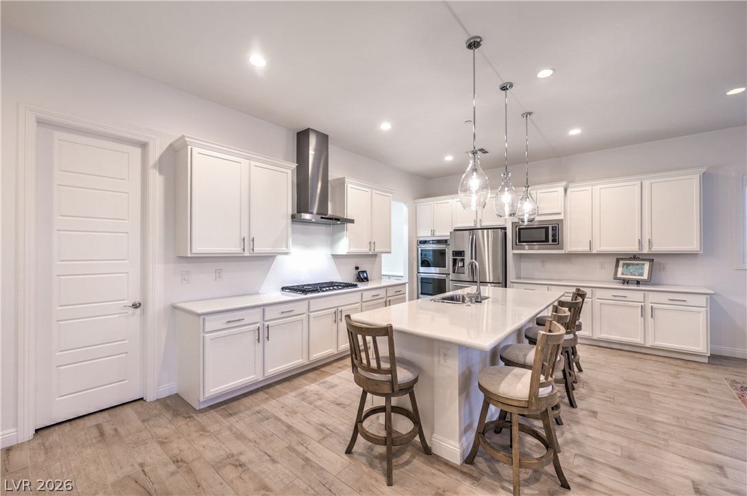 Gourmet Island Kitchen with Quartz Countertops, Breakfast Bar, Abundant Cabinetry, Walk-In Pantry, Recessed Lighting, Pendant Lighting, Touchless Faucet, and Stainless-Steel Appliances including B/I Double Oven w/ Convection Feature, Gas Cooktop, Upgraded Hood, Dishwasher, Microwave, and Refrigerator