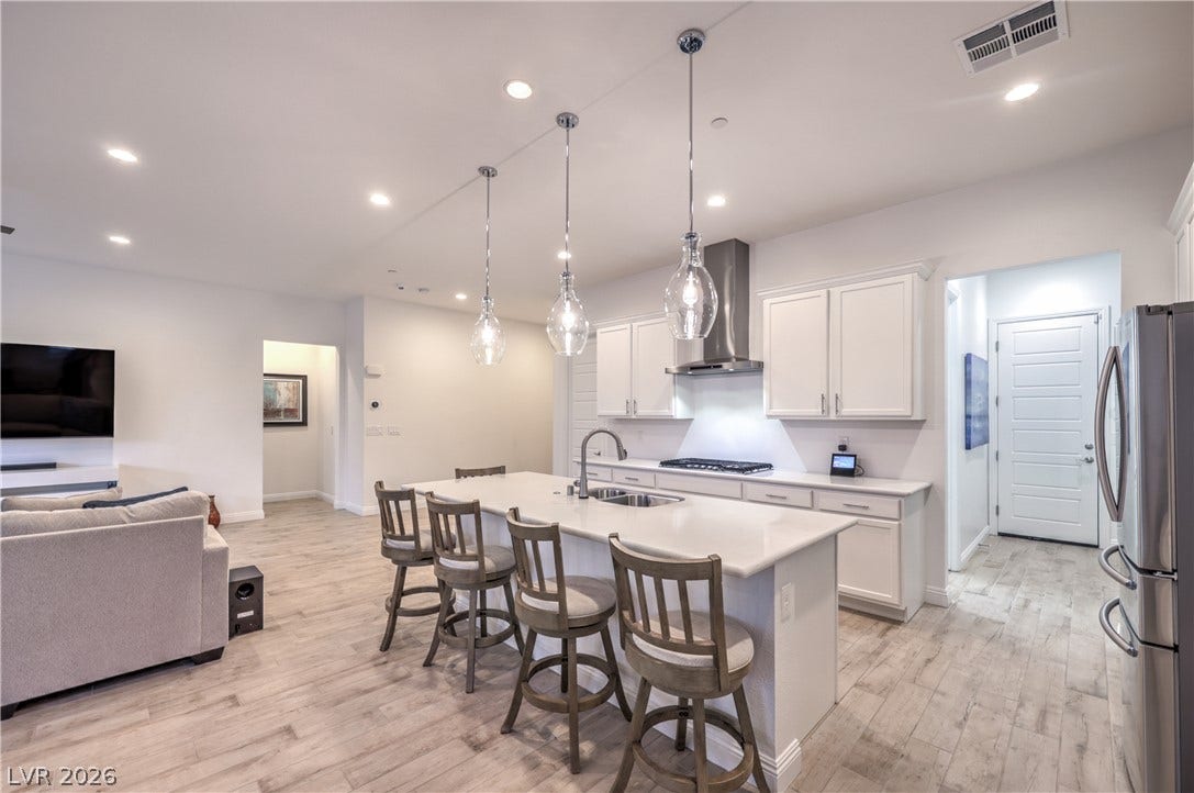 Gourmet Island Kitchen with Quartz Countertops, Breakfast Bar, Abundant Cabinetry, Walk-In Pantry, Recessed Lighting, Pendant Lighting, Touchless Faucet, and Stainless-Steel Appliances including B/I Double Oven w/ Convection Feature, Gas Cooktop, Upgraded Hood, Dishwasher, Microwave, and Refrigerator