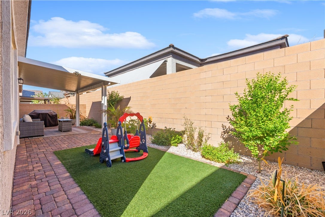 848 Purser Street, Henderson, NV 89011 A private walled backyard features a brick paver patio and a covered outdoor living space.