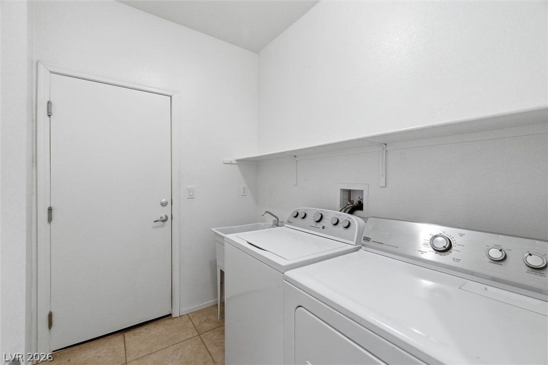 4911 S Castello Way, Pahrump, NV 89061 A functional laundry area contains a utility sink, overhead shelving, and tile flooring.