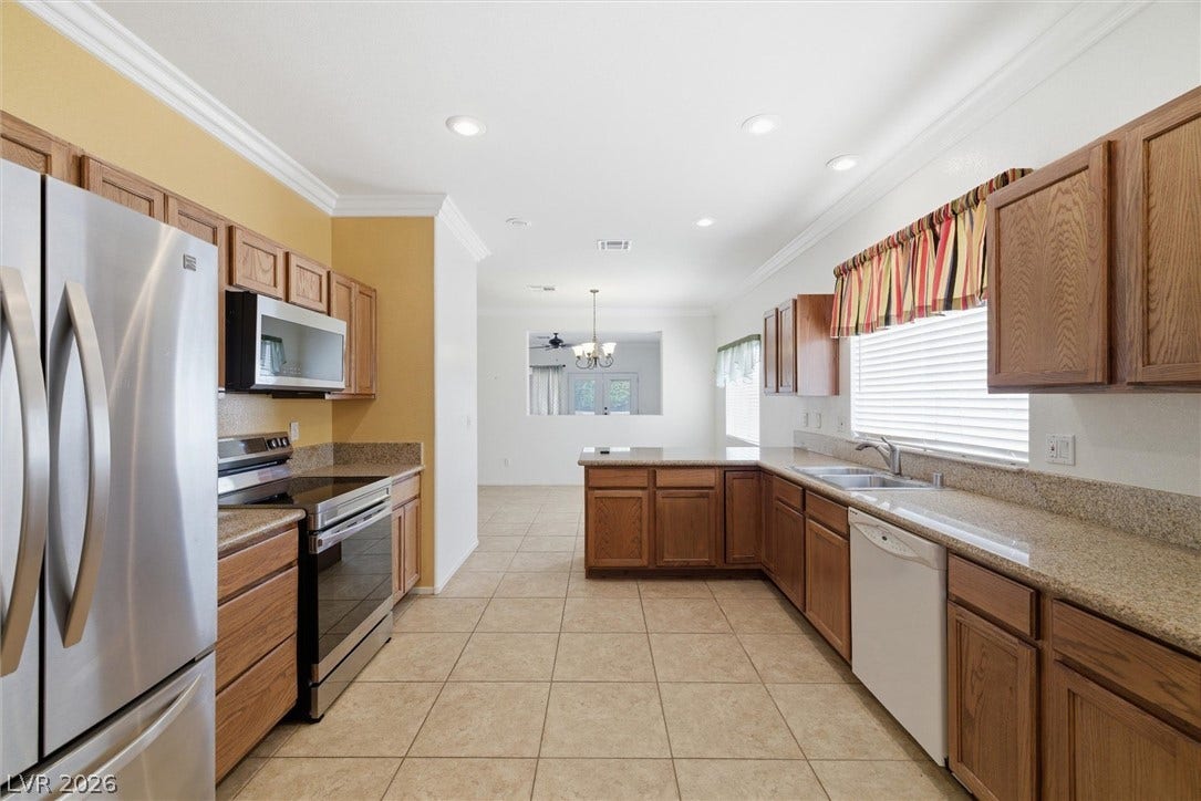4911 S Castello Way, Pahrump, NV 89061 Ample wooden cabinetry and stone countertops wrap around this wide tiled kitchen space.