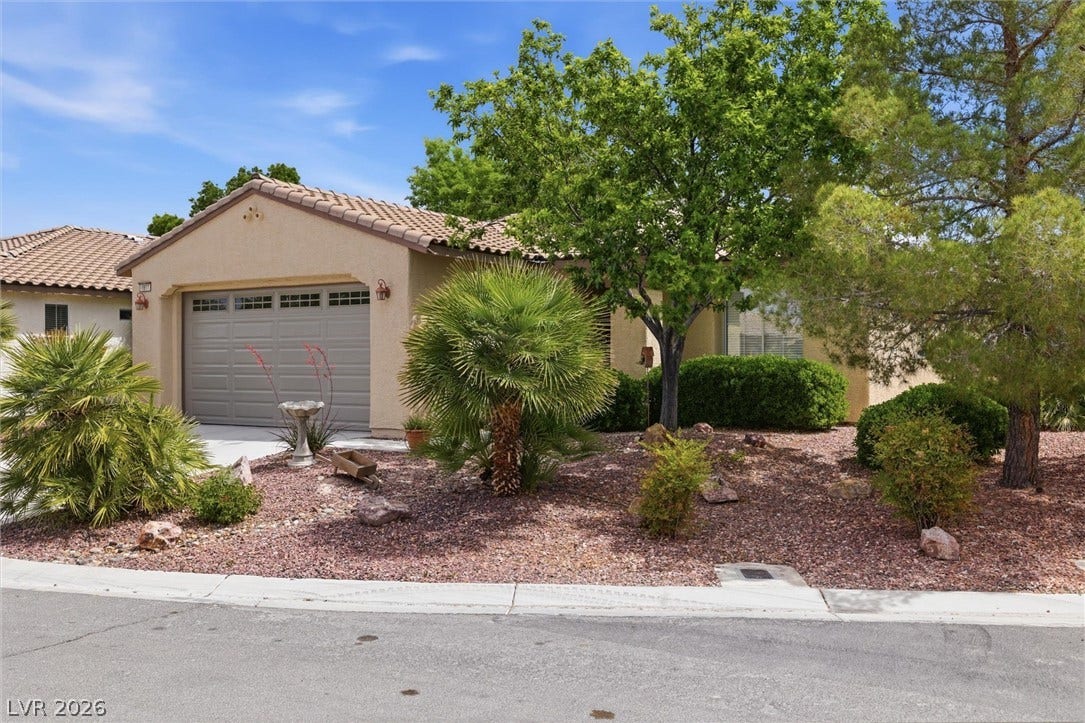 4911 S Castello Way, Pahrump, NV 89061 Desert landscaping and mature trees frame the facade of this tile-roof home.