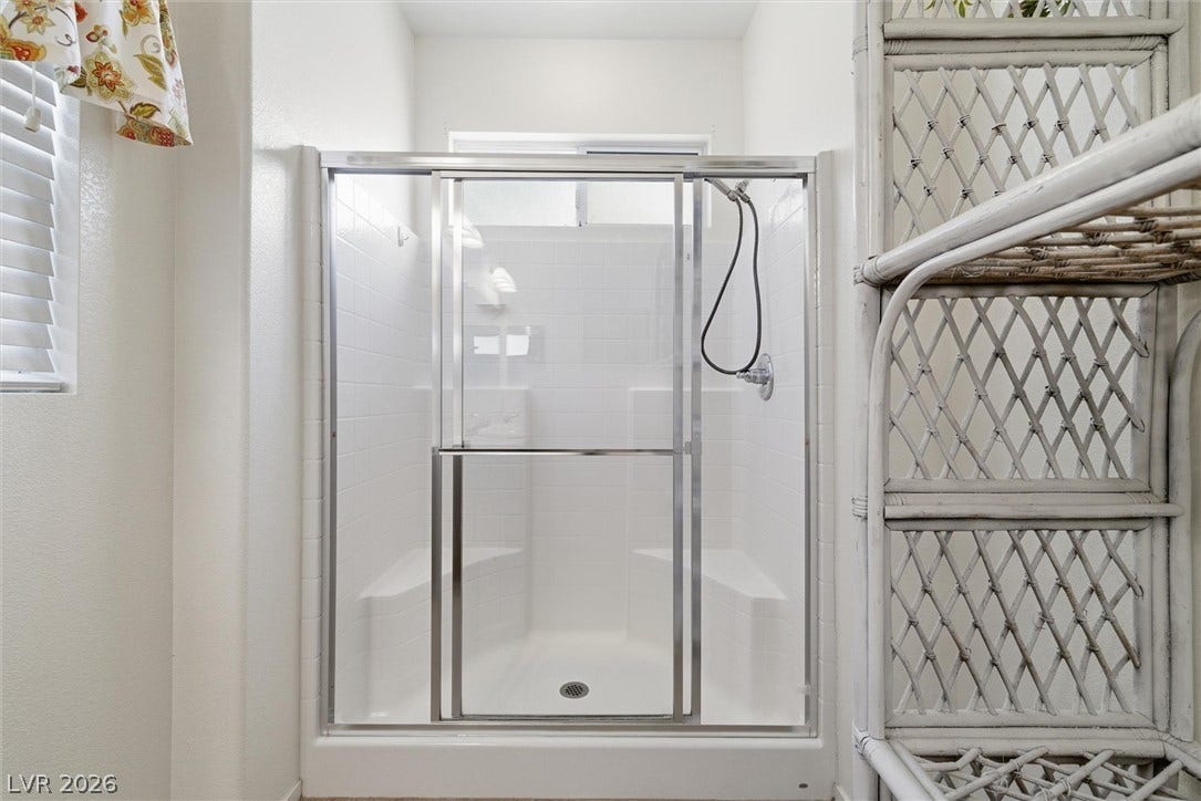 4911 S Castello Way, Pahrump, NV 89061 A framed glass walk-in shower features built-in corner benches and classic white tile surrounds.