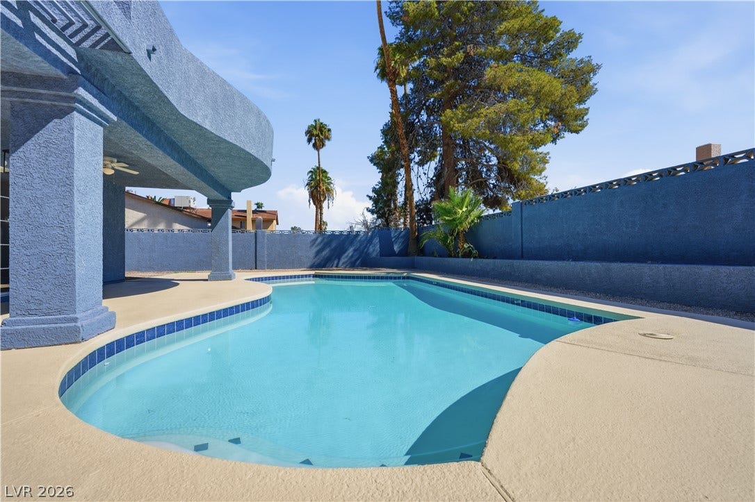 1707 Mapleton Lane, Las Vegas, NV 89119 A sparkling in-ground pool is framed by matching stucco walls and mature palms.