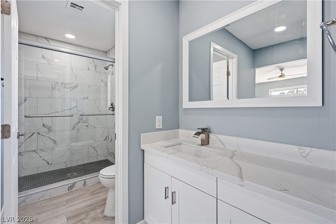 1707 Mapleton Lane, Las Vegas, NV 89119 Modern stone countertops and a tiled walk-in shower elevate this updated bathroom design.