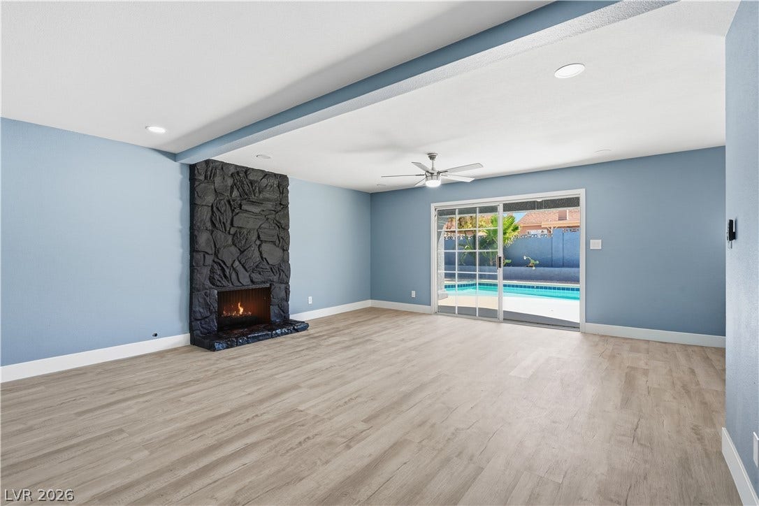 1707 Mapleton Lane, Las Vegas, NV 89119 Sliding glass doors connect a spacious living room to a sparkling outdoor pool area.